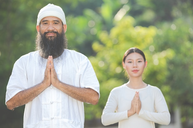 People in white outfit putting  their own hands in a prayer position