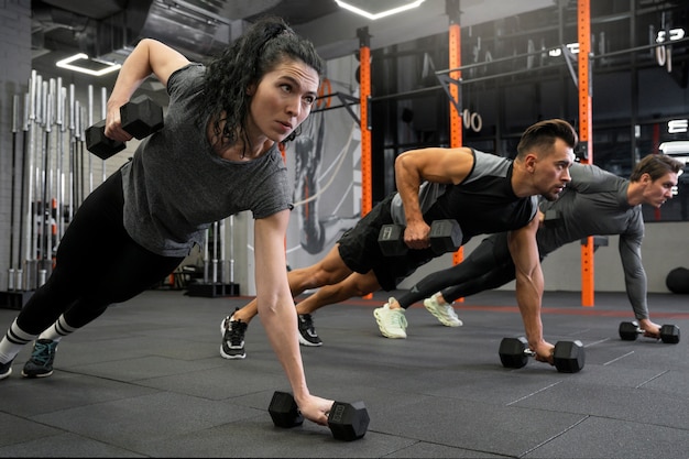 Free photo people working out indoors together with dumbbells