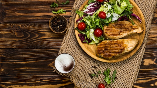 Pepper and beer near salad and chicken