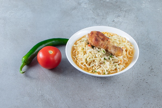 Pepper, tomatoes and noodle bowl, on the marble background. 