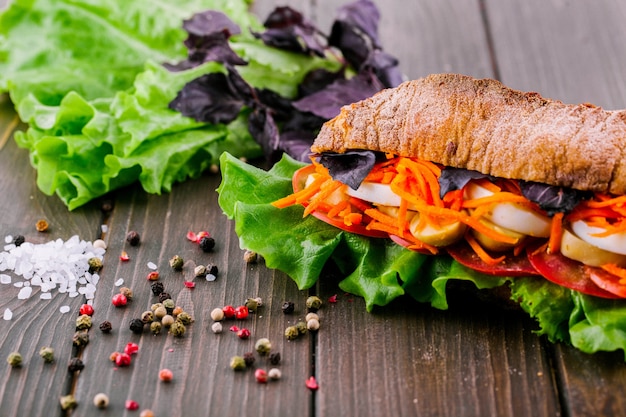 Free photo peppercorns, salt and greenery lie before healthy wholemeal sandwich