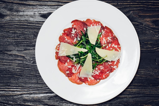 Pepperoni slices with parmesan and greenery.