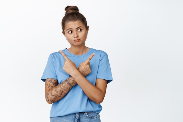 Free Photo perplexed girl deciding between two options pointing sideways and looking at right side standing over white background