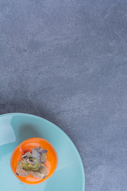 Persimmon fruits on a plateon marble table.