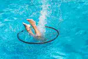 Free photo person among hula hoop diving in pool