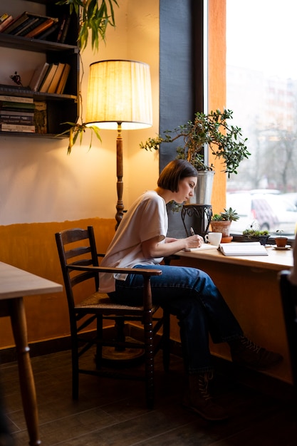 Free Photo person in a cafe enjoying a book