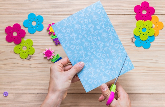 Free photo a person cutting craft paper with scissor on table