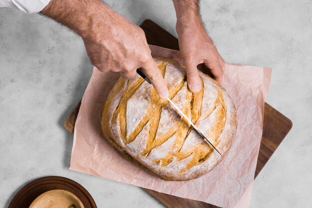 Person cutting half of bread top view