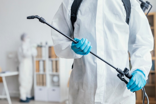 Person disinfecting a dangerous area while wearing a protective suit