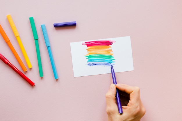 Free photo person drawing rainbow with felt pen