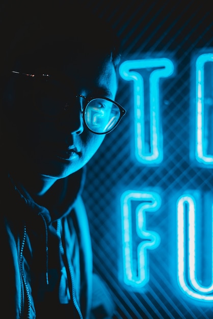 Free Photo person in eyeglasses beside blue neon signage