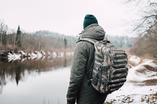 Person in front of the lake surrounded by trees during winter