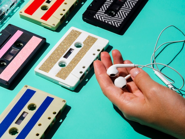 Person holdig headphones near cassette tape collection