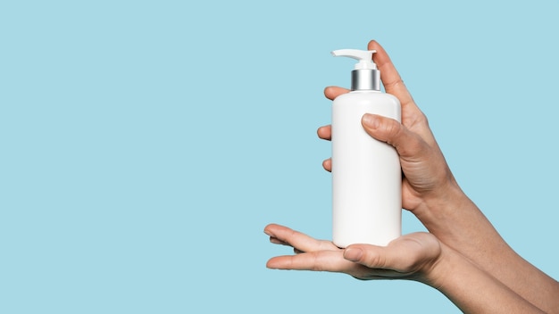 Person holding a bottle of liquid soap with copy space