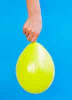 Free photo person holding bright yellow balloon