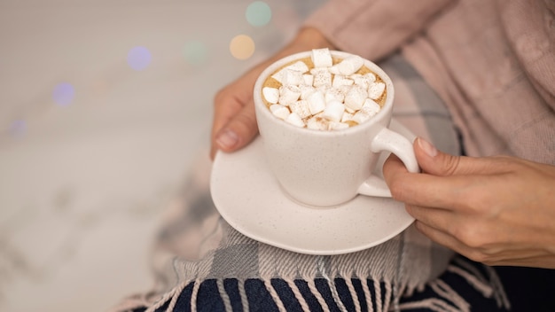 Free Photo person holding cup of hot cocoa with marshmallows