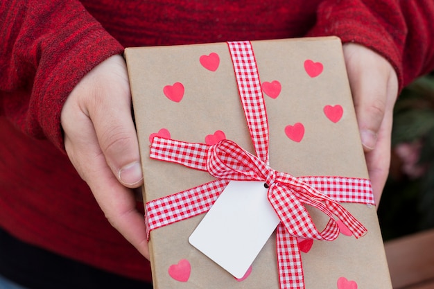 Free Photo person holding gift box with hearts in hands