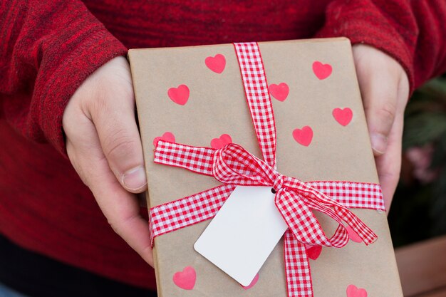 Person holding gift box with hearts in hands