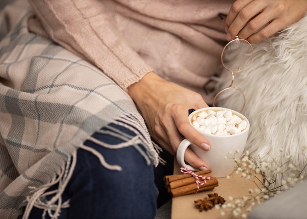 Free photo person holding glasses and cup of hot cocoa with marshmallows