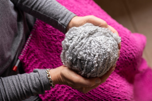 Free Photo person holding a grey thread for knitting