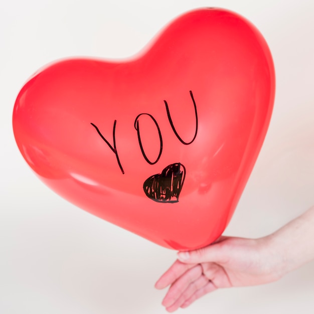 Free photo person holding heart balloon with you inscription