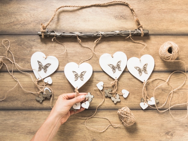 Free photo a person holding heart windchimes on wooden plank with spool