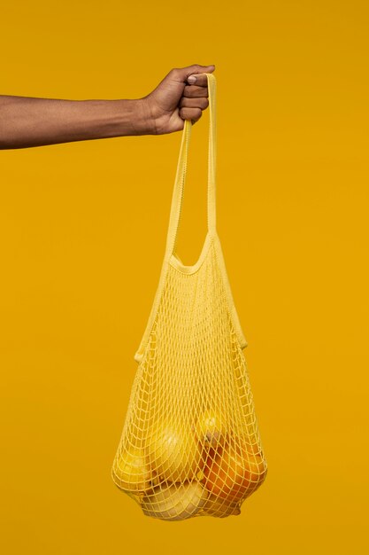 Person holding mesh bag with citrus fruit