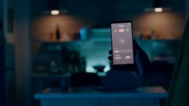 Person holding mobile phone with high tech application in smart house features controlling lights with wireless device