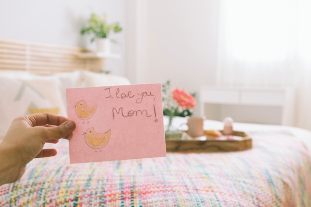 Free photo person holding paper with i love you mom inscription