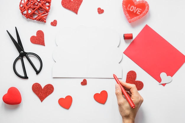 Free photo person holding pen above table with hearts