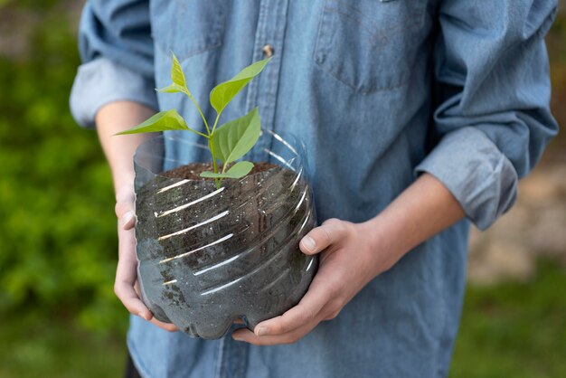 Person holding a plant in a plastic pot