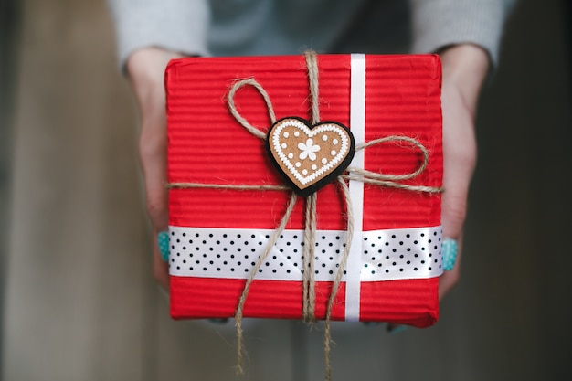 Free photo person holding red gift with a golden heart with a star in the center