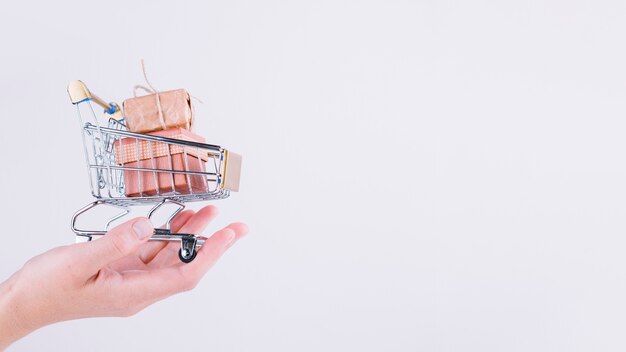 Person holding small grocery cart with gift boxes