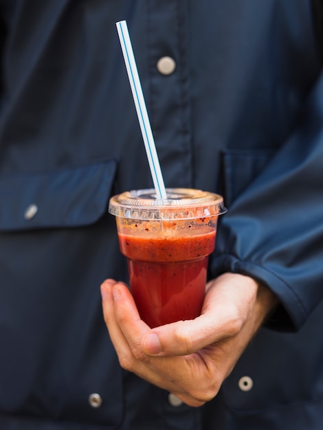 Free photo a person holding smoothie in plastic disposable cup with straw