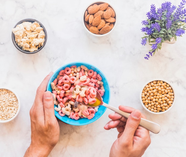 Free Photo person holding spoon with cereal above blue bowl