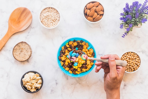 Free Photo person holding spoon with cereal above bowl