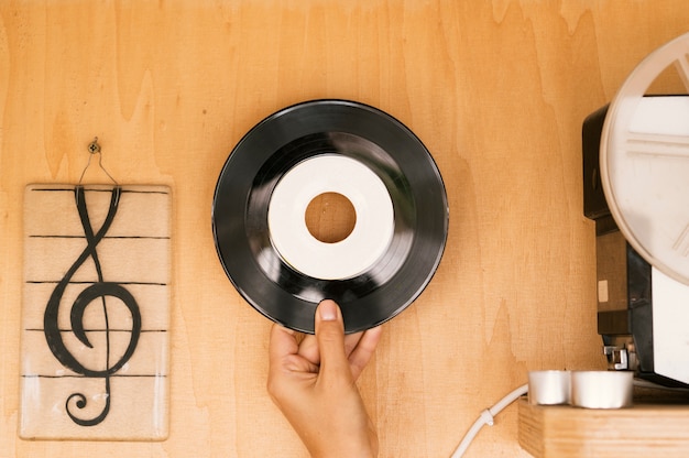 Free photo person holding vinyl disk on wooden table