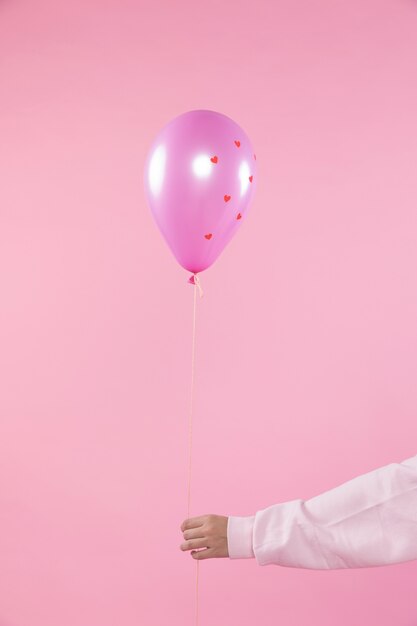 Person holding violet balloon with ornament hearts and thread