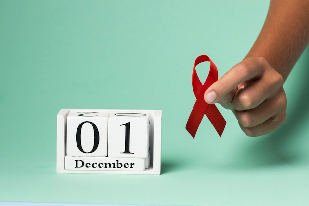 Free photo person holding an world aids day ribbon symbol with the event date