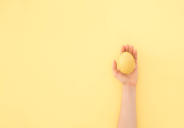 Person holding yellow Easter egg in hand 