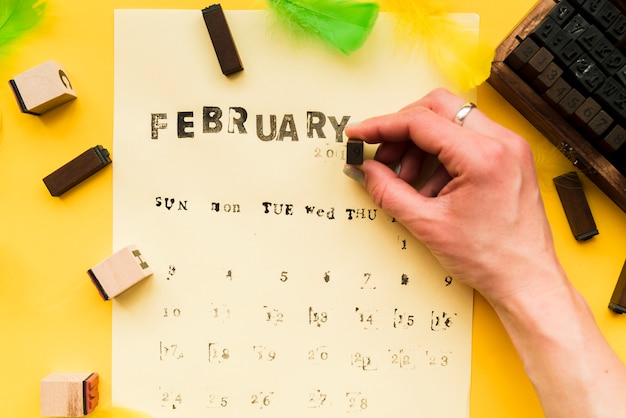 A person making the february calendar with typographic blocks on yellow background