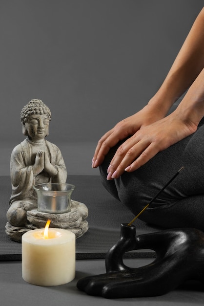 Free photo person meditating next to buddha statuette