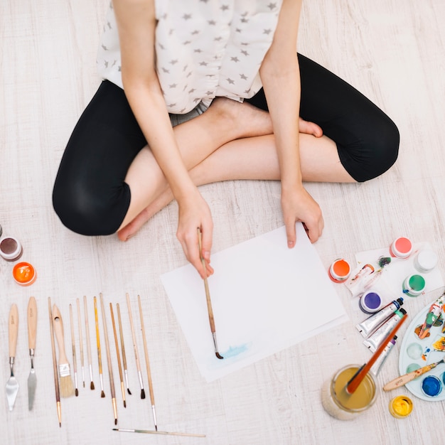 Person painting with aquarelle on floor