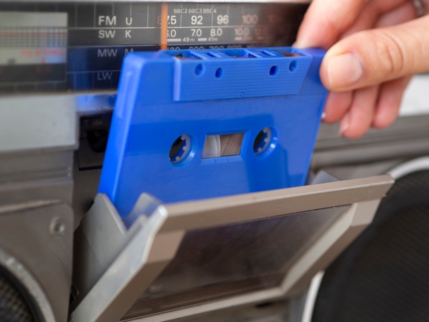 Free Photo person placing blue cassette tape in music player