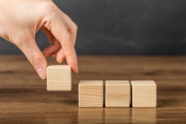 Person placing a wooden cube next to others