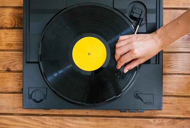 Free photo person playing a vinyl disk on vintage music player