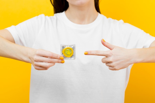 Free photo person pointing to a yellow condom