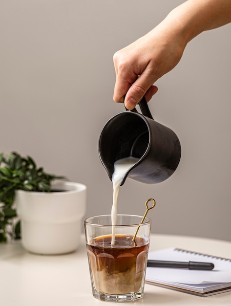 Free photo person pouring cream in coffee glass