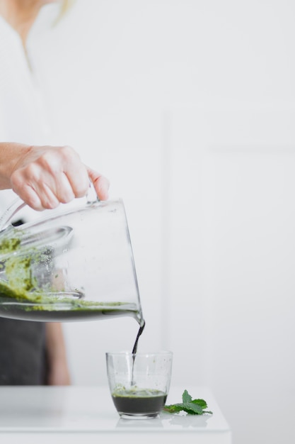 Free Photo person pouring green smoothie