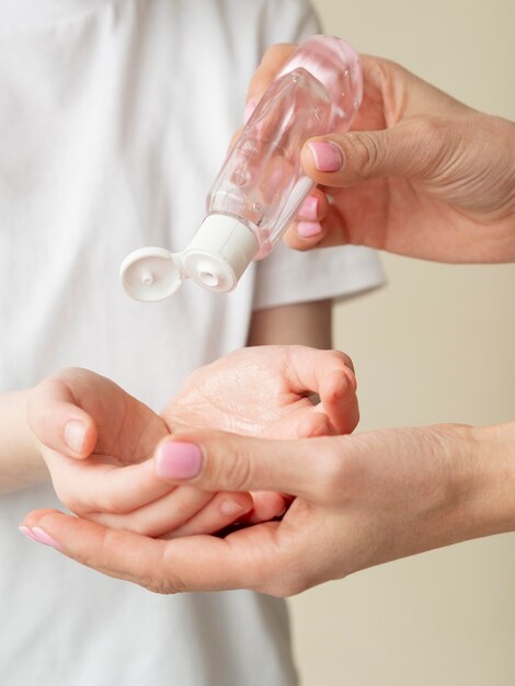 Person pouring hand sanitizer in child's hands